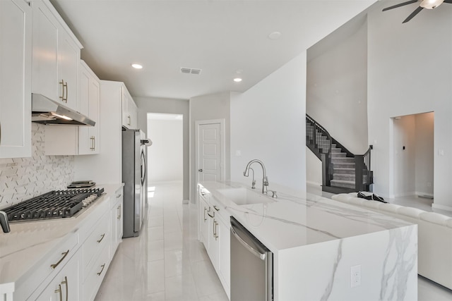 kitchen featuring white cabinetry, stainless steel appliances, sink, and light stone counters