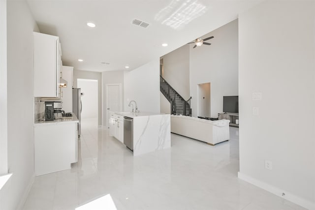 kitchen with sink, ceiling fan, white cabinetry, stainless steel appliances, and light stone countertops