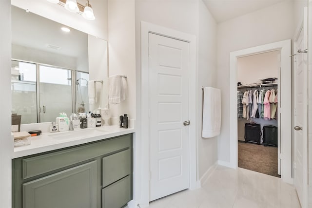 bathroom featuring a shower with door, vanity, and tile patterned floors