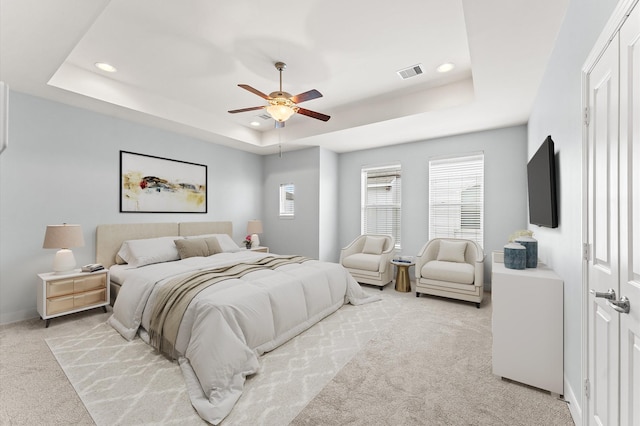 carpeted bedroom featuring ceiling fan and a raised ceiling