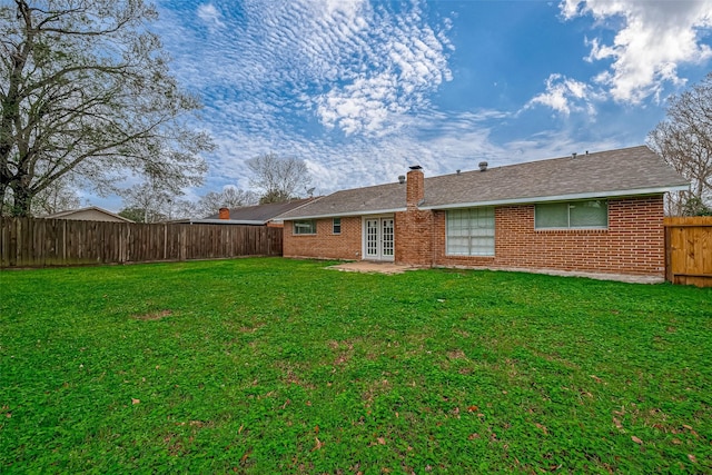 rear view of house with a lawn and french doors