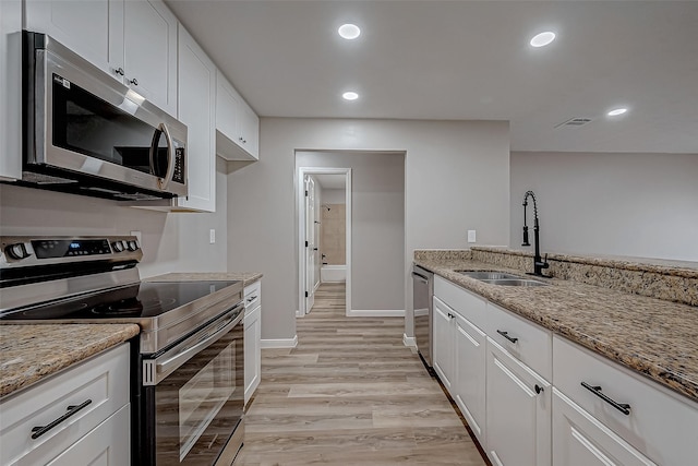 kitchen featuring white cabinetry, appliances with stainless steel finishes, light stone countertops, and sink