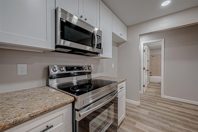 kitchen with light stone counters, light hardwood / wood-style flooring, stainless steel appliances, and white cabinets