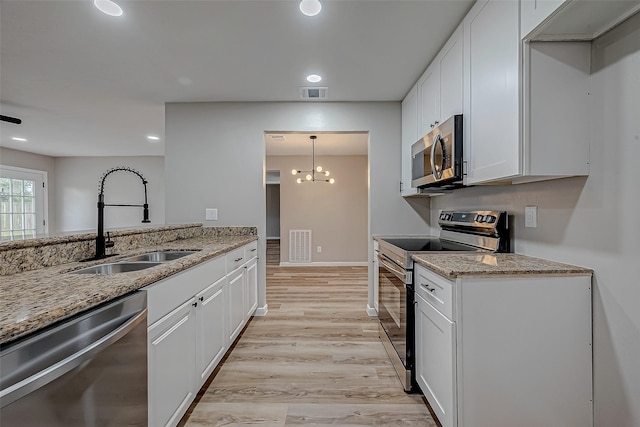 kitchen featuring stainless steel appliances, white cabinetry, light stone countertops, and sink