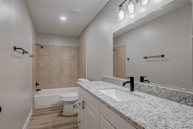 full bathroom with tiled shower / bath, hardwood / wood-style floors, vanity, and toilet