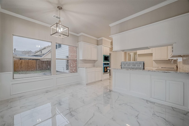 kitchen featuring built in microwave, sink, stainless steel oven, pendant lighting, and white cabinets