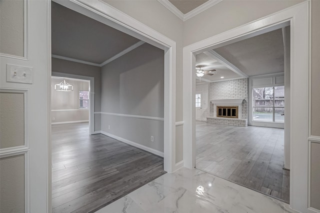 interior space featuring a brick fireplace, crown molding, hardwood / wood-style floors, and ceiling fan