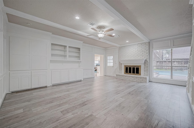 unfurnished living room featuring ceiling fan, a fireplace, ornamental molding, a textured ceiling, and light wood-type flooring