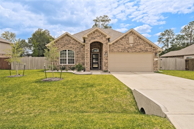 view of front of house featuring brick siding, concrete driveway, a front yard, fence, and a garage