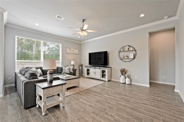 living room featuring ceiling fan, wood finished floors, visible vents, baseboards, and ornamental molding