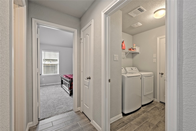 washroom with laundry area, visible vents, baseboards, wood tiled floor, and separate washer and dryer