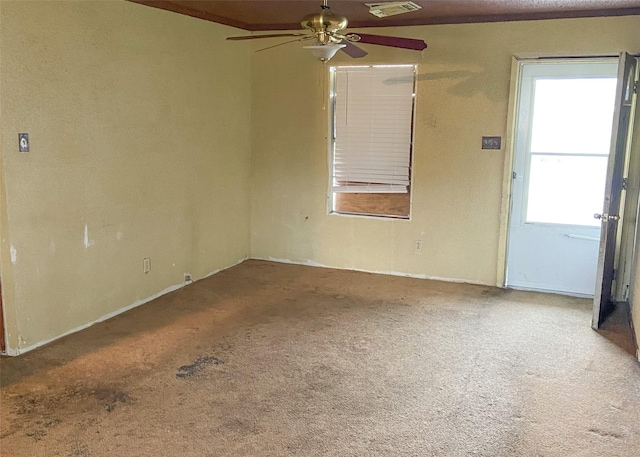 empty room featuring carpet flooring, visible vents, and a ceiling fan