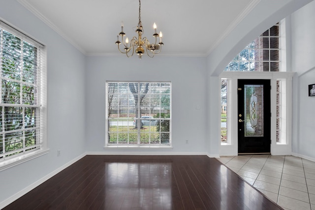 foyer featuring an inviting chandelier, plenty of natural light, and ornamental molding