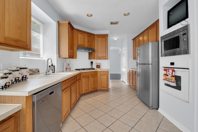 kitchen with stainless steel appliances, tasteful backsplash, sink, and light tile patterned floors