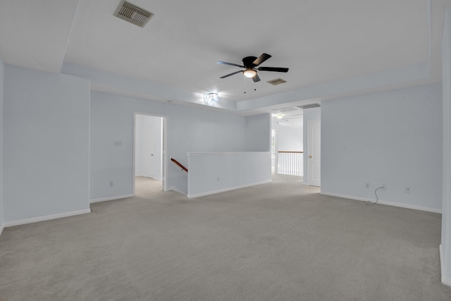 carpeted spare room featuring ceiling fan and a tray ceiling