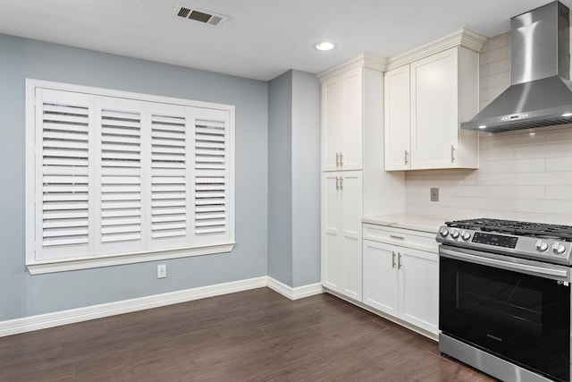 kitchen with wall chimney range hood, stainless steel gas range, dark hardwood / wood-style floors, tasteful backsplash, and light stone countertops