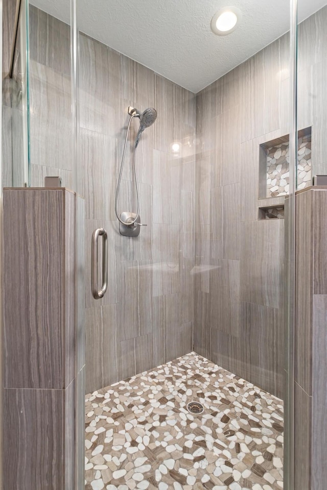 bathroom featuring an enclosed shower and a textured ceiling