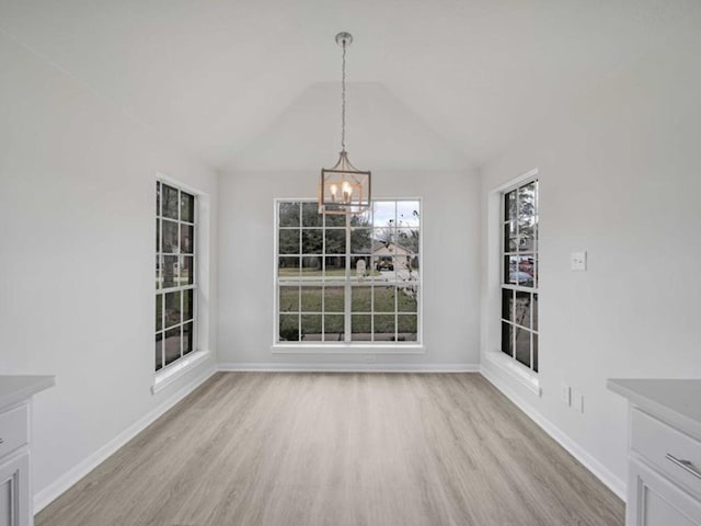 unfurnished dining area featuring lofted ceiling, an inviting chandelier, light wood-style flooring, and baseboards