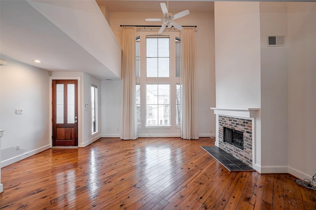 unfurnished living room featuring a brick fireplace, visible vents, light wood-style flooring, and baseboards