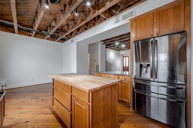 kitchen with dark wood-style floors, a center island, wooden counters, and stainless steel fridge with ice dispenser