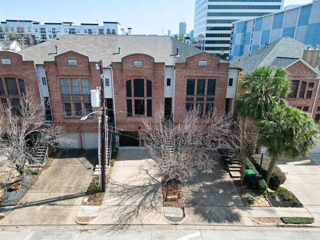 view of building exterior with concrete driveway, an attached garage, and a city view