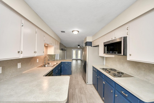 kitchen featuring sink, blue cabinetry, appliances with stainless steel finishes, white cabinetry, and kitchen peninsula