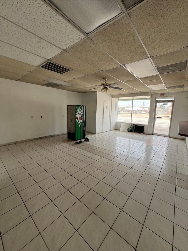 tiled empty room featuring ceiling fan and a paneled ceiling