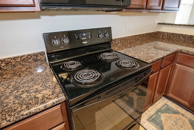 kitchen with black range with electric stovetop and dark stone counters