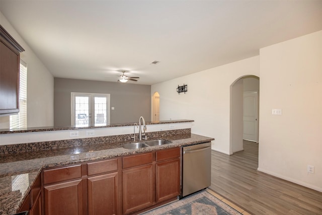 kitchen with dark stone countertops, sink, hardwood / wood-style flooring, and dishwasher