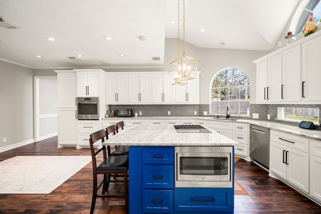 kitchen with blue cabinetry, a kitchen breakfast bar, white cabinetry, stainless steel appliances, and lofted ceiling