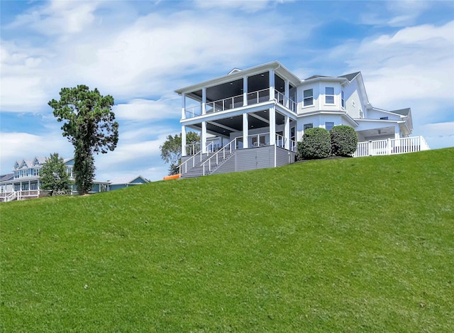 rear view of house featuring a yard and a sunroom