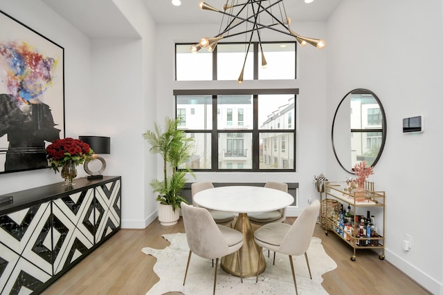 dining space with a towering ceiling and light hardwood / wood-style floors