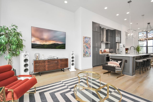 living room featuring an inviting chandelier, light hardwood / wood-style flooring, and sink