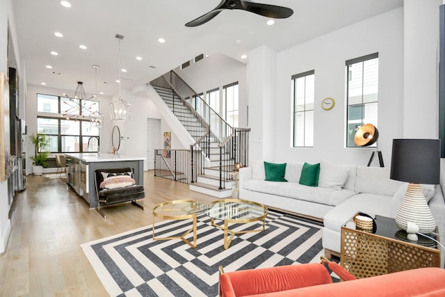 living room featuring sink, light hardwood / wood-style floors, plenty of natural light, and ceiling fan with notable chandelier