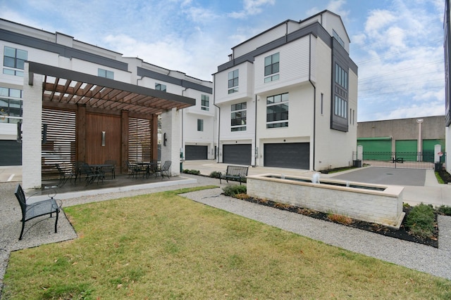 back of house featuring a garage, a lawn, a pergola, and a patio area