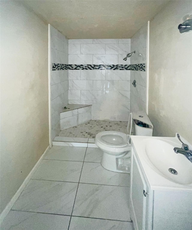 bathroom with vanity, toilet, and tiled shower