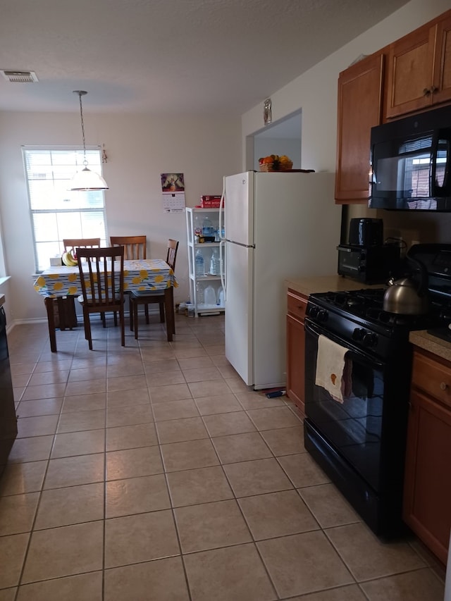 kitchen featuring hanging light fixtures, light tile patterned floors, and black appliances