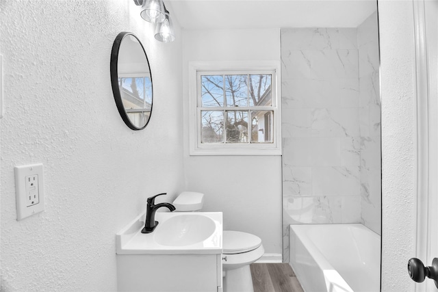 full bathroom featuring vanity, tiled shower / bath, hardwood / wood-style flooring, and toilet