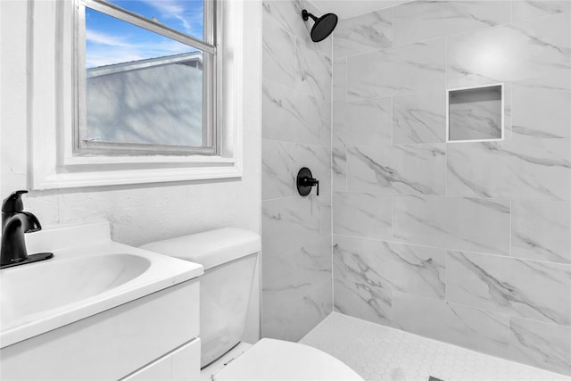 bathroom with vanity, a tile shower, and toilet