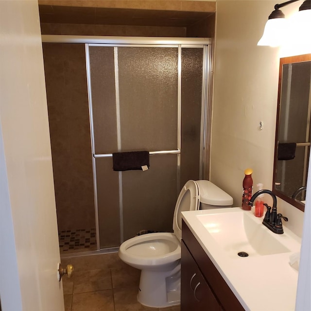 bathroom featuring tile patterned flooring, vanity, a shower with door, and toilet