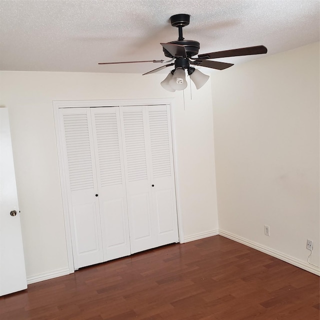 unfurnished bedroom featuring ceiling fan, a textured ceiling, dark hardwood / wood-style flooring, and a closet