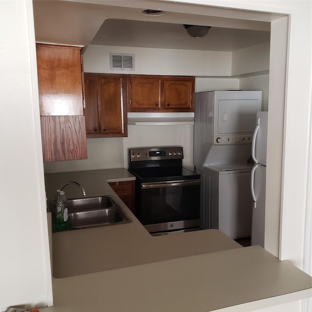 kitchen featuring white refrigerator, stacked washer and dryer, stainless steel electric range oven, and sink