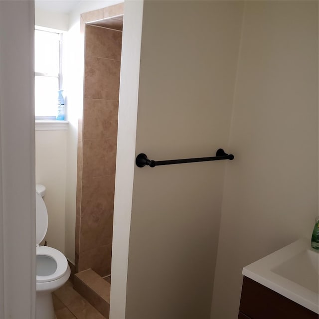 bathroom with tile patterned floors, toilet, vanity, and a tile shower