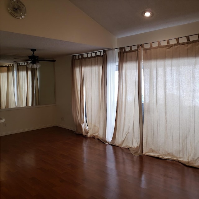 empty room featuring dark wood-type flooring, vaulted ceiling, and ceiling fan