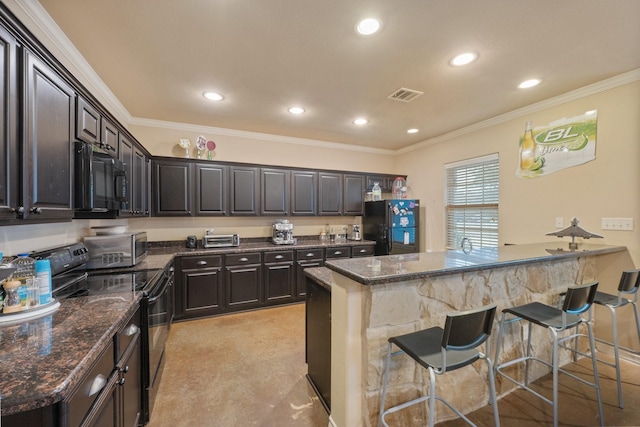 kitchen with a breakfast bar, dark brown cabinets, ornamental molding, black appliances, and dark stone counters