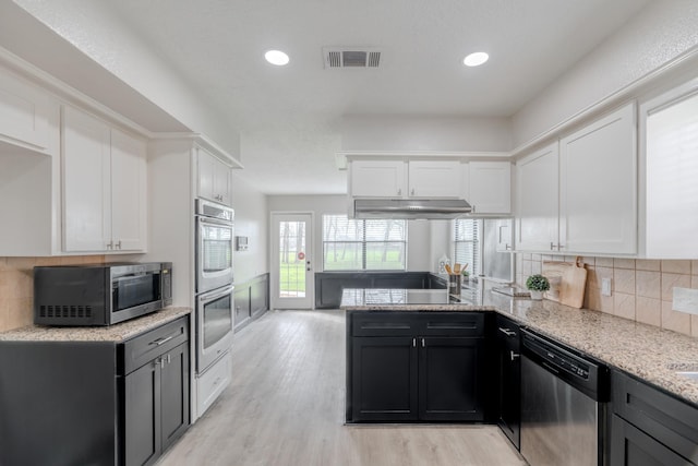 kitchen featuring stainless steel appliances, tasteful backsplash, light stone counters, light hardwood / wood-style floors, and white cabinets