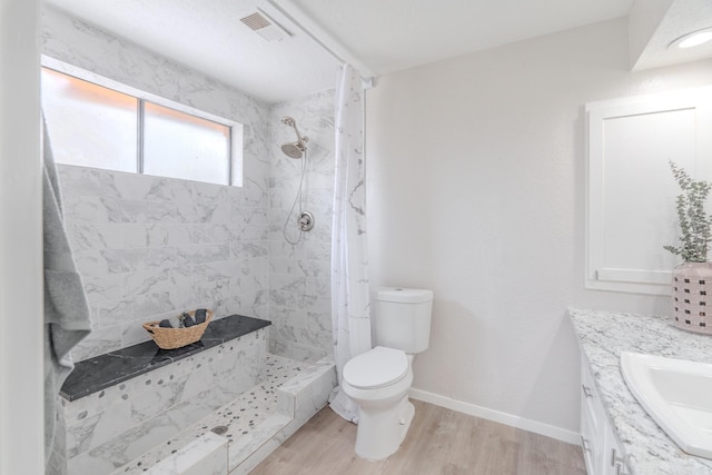 bathroom with vanity, hardwood / wood-style floors, toilet, and a tile shower