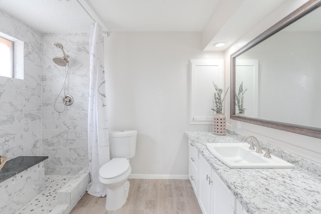 bathroom featuring vanity, wood-type flooring, a tile shower, and toilet