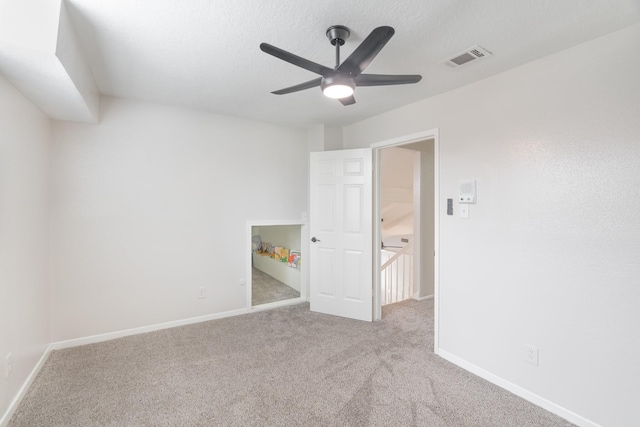 unfurnished bedroom featuring light carpet, a textured ceiling, and ceiling fan