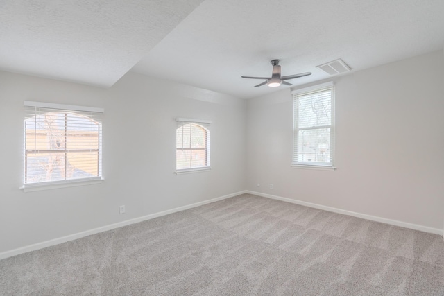 carpeted empty room with ceiling fan and a textured ceiling